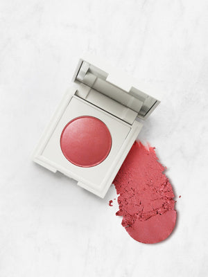 Fard à joues rose poudré dans boîtier blanc, texture poudreuse sur fond marbre